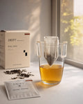 Yunnan Dian Hong drip bag tea brewing in glass cup with product box and loose tea leaves